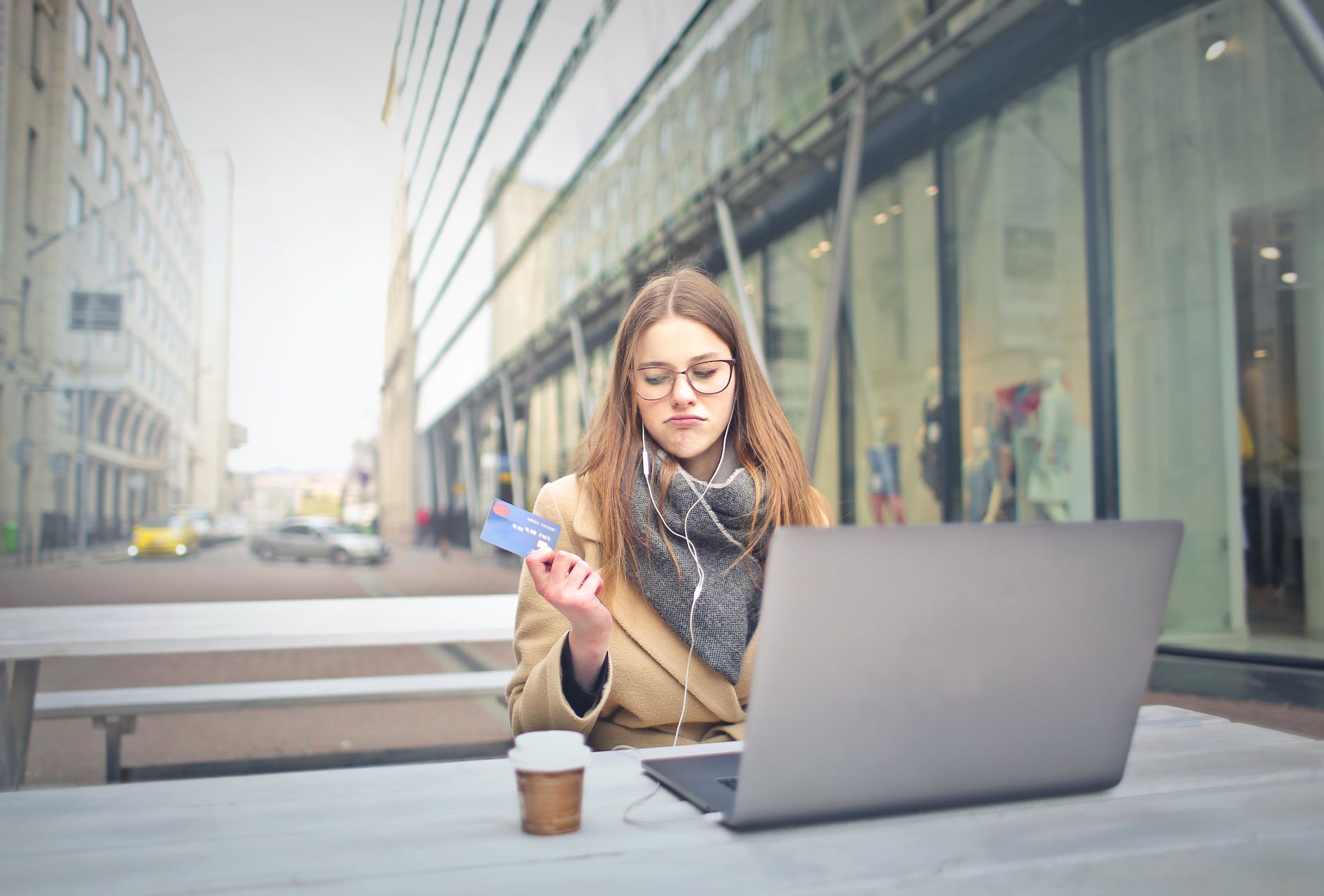 woman in brown coat holding a bank card